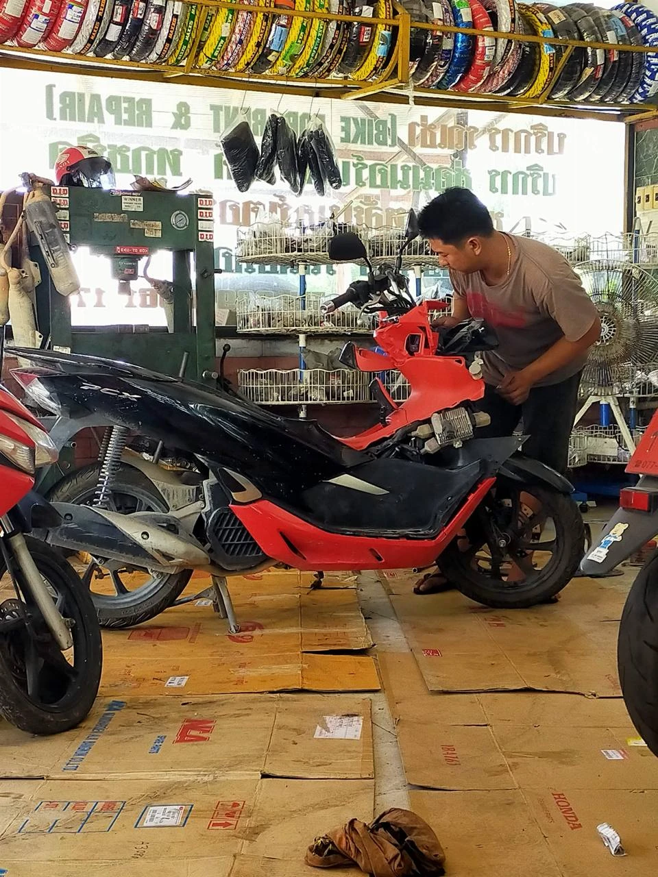 Механик меняет пластик на скутере Honda PCX в мастерской