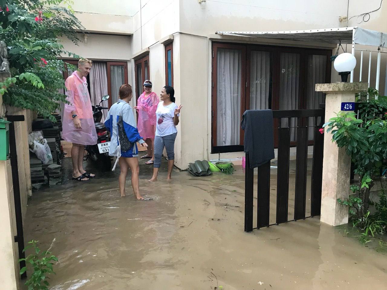 Люди стоят в воде у калитки во время наводнения на Самуи
